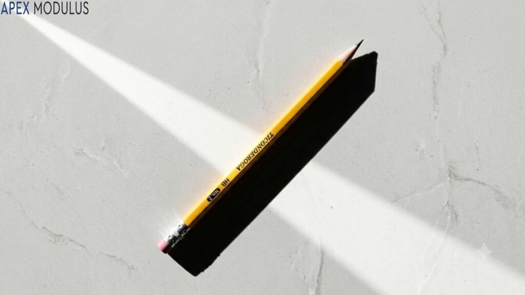 A single sharpened yellow pencil lies diagonally on a light grey marble surface, casting a long, distinct shadow.